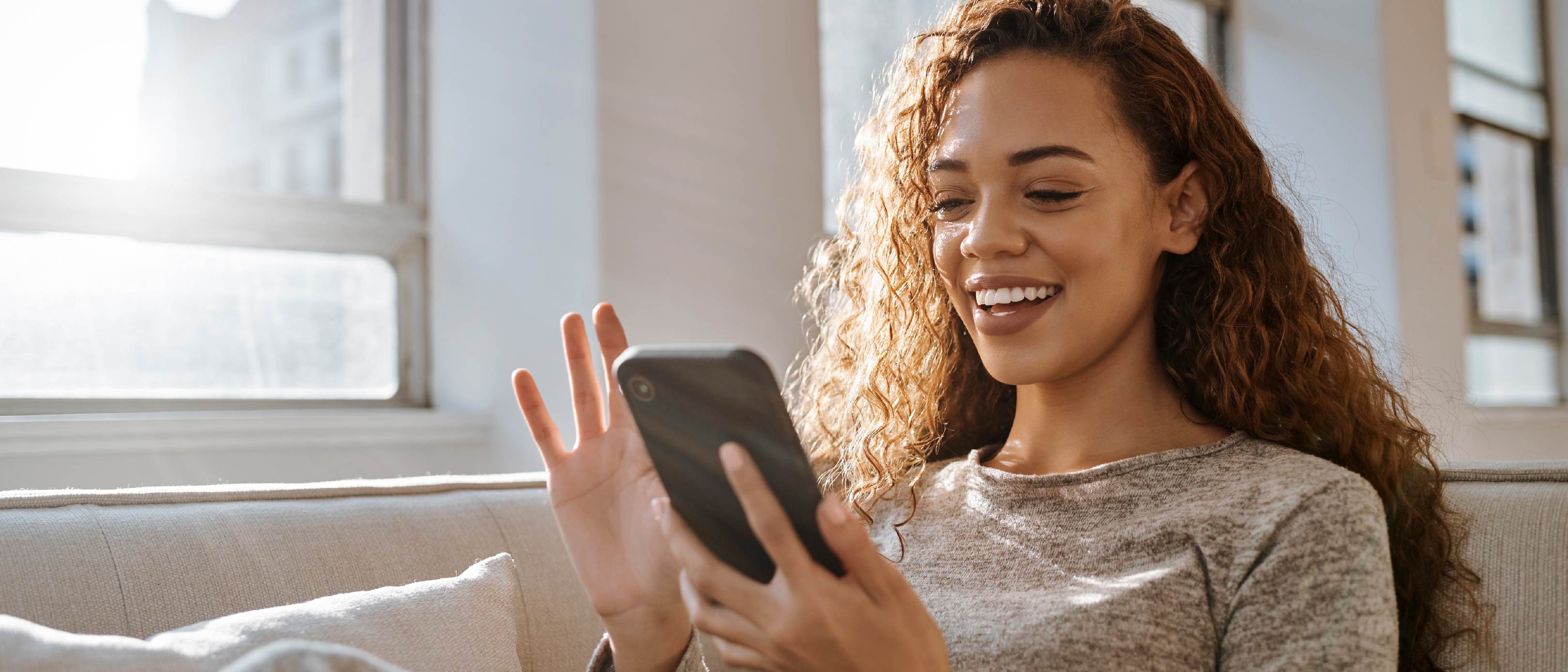 Person reading mobile phone on couch.'